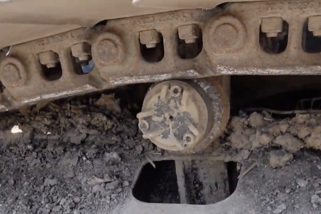 Worn excavator carrier roller, mounted, field photo